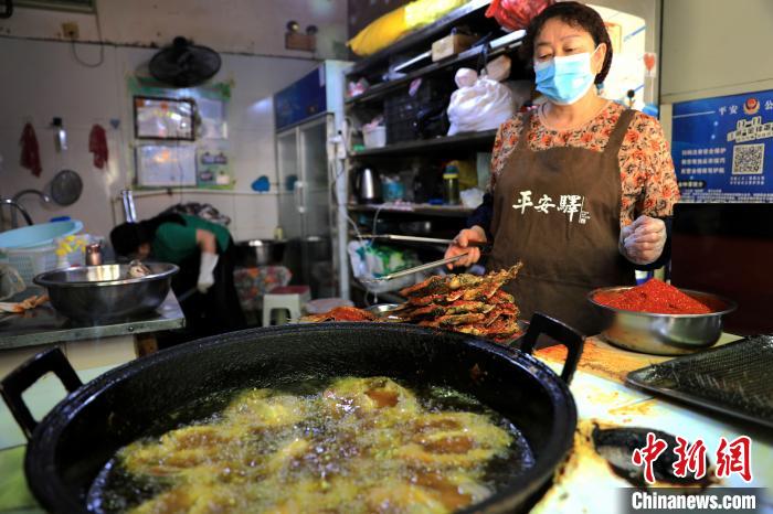 圖為平安驛·河湟民俗文化體驗(yàn)地內(nèi)的商戶炸干板魚。　薛蒂 攝